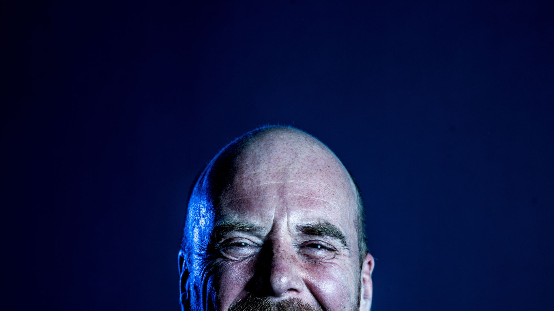 Lachende Steven Mahieu in blauwe kledij en blauw licht