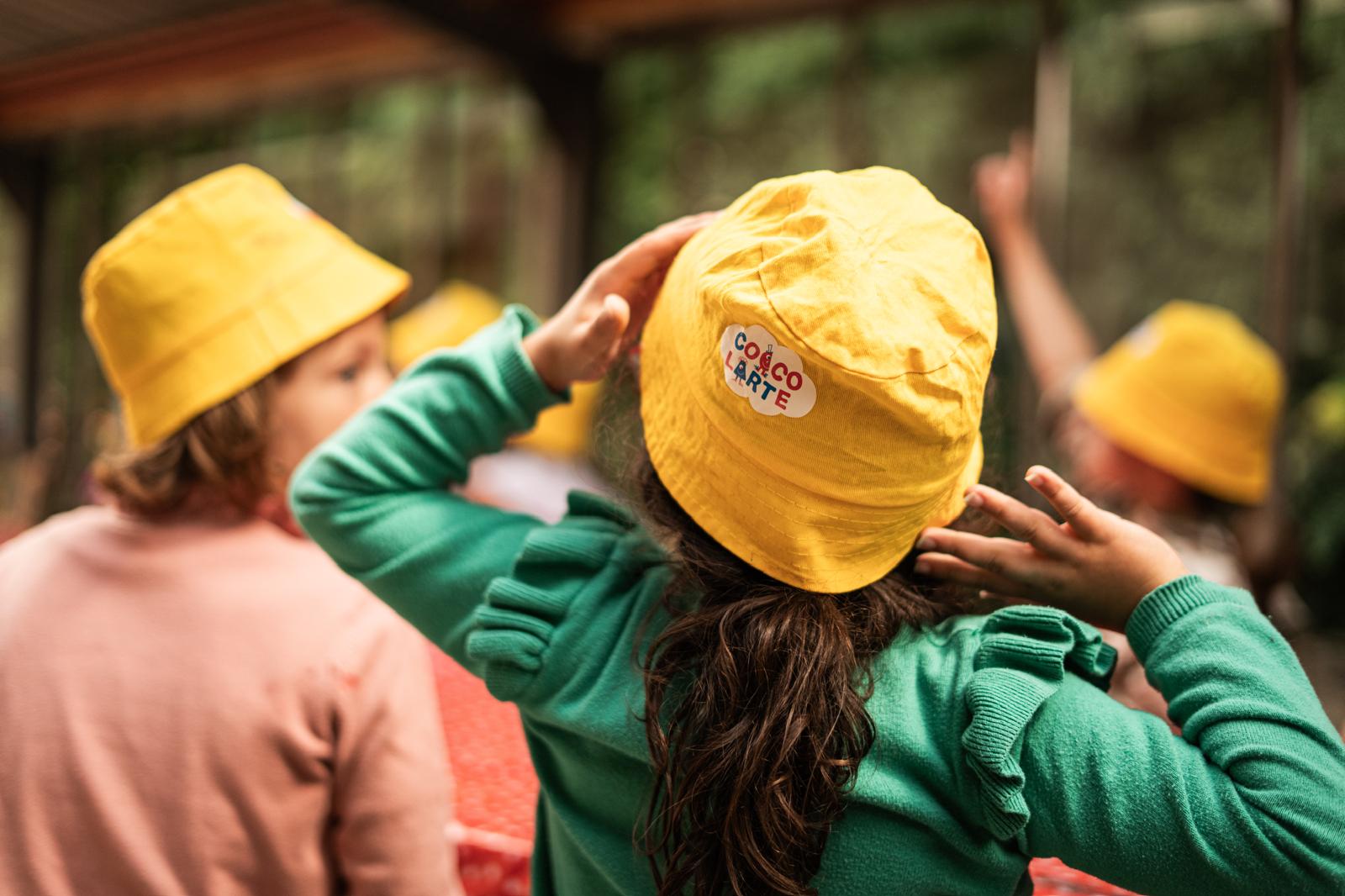 De achterkant van een kind met een groene T-shirt en geel hoedje