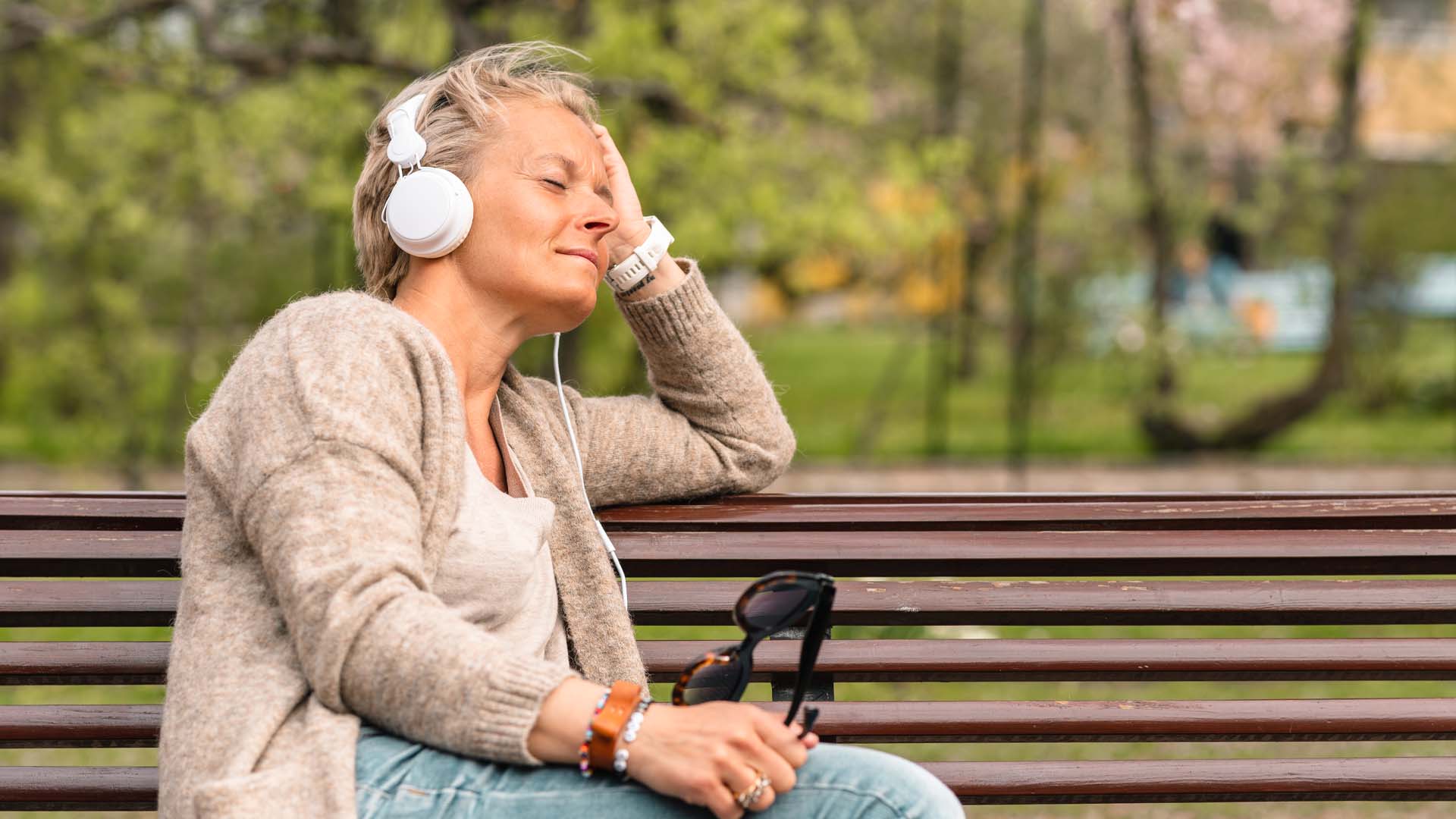 foto rustende dame op een bankje aan het genieten van de muziek