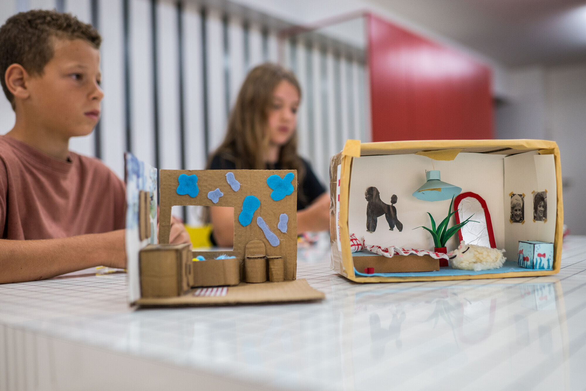 Kartonnen knutselwerkjes met kinderen op de achtergrond