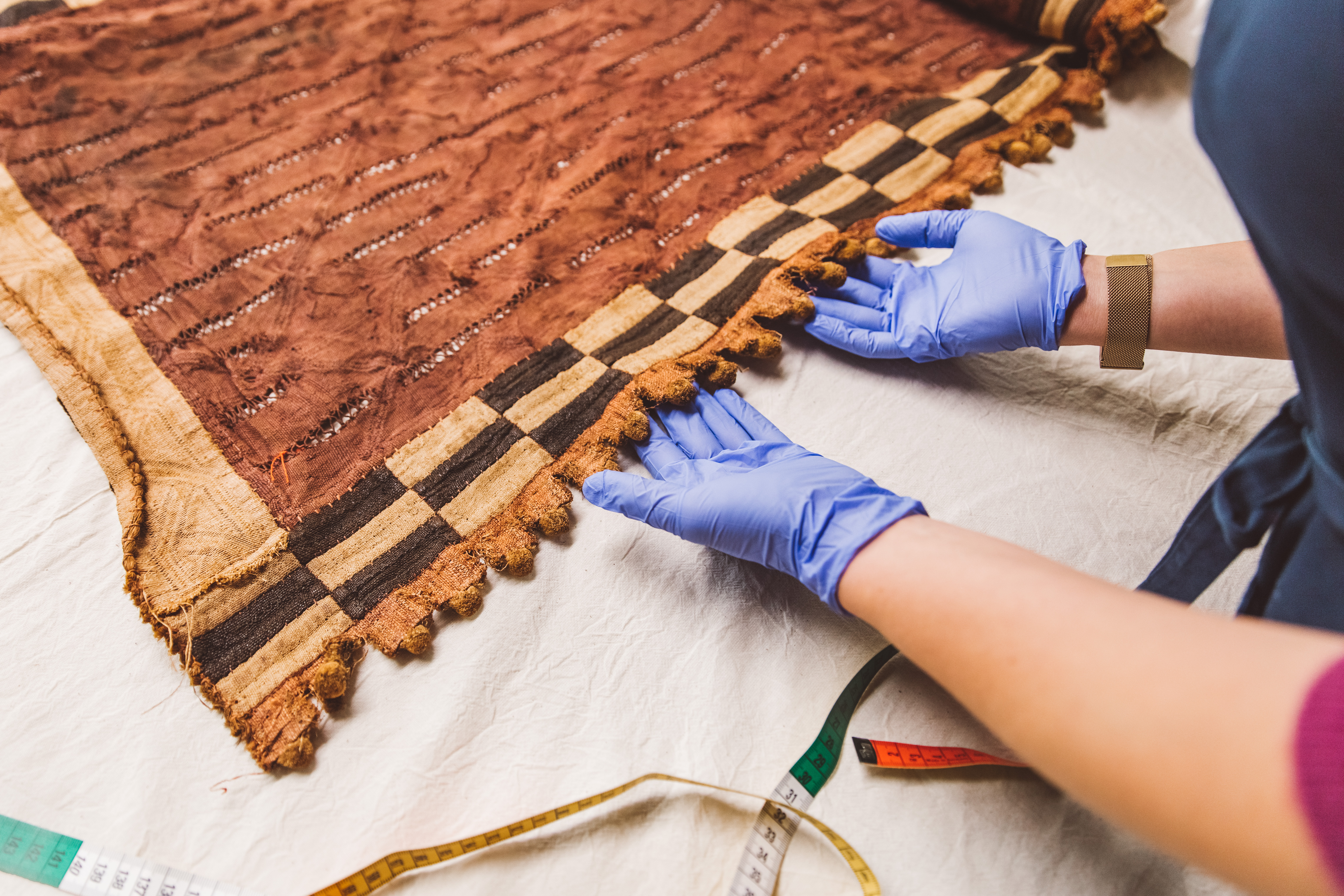 Medewerker van het Collectiebeheerteam onderzoekt een geweven doek.