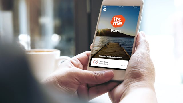 Persoon die smartphone vasthoudt, waarop het login-scherm van itsme te zien is