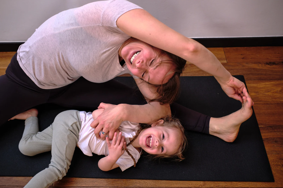 Ouder en kind lachen terwijl ze yoga doen