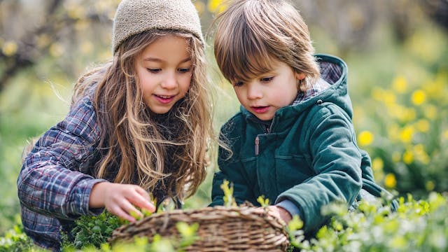 twee kinderen zoeken paaseieren in een groene omgeving