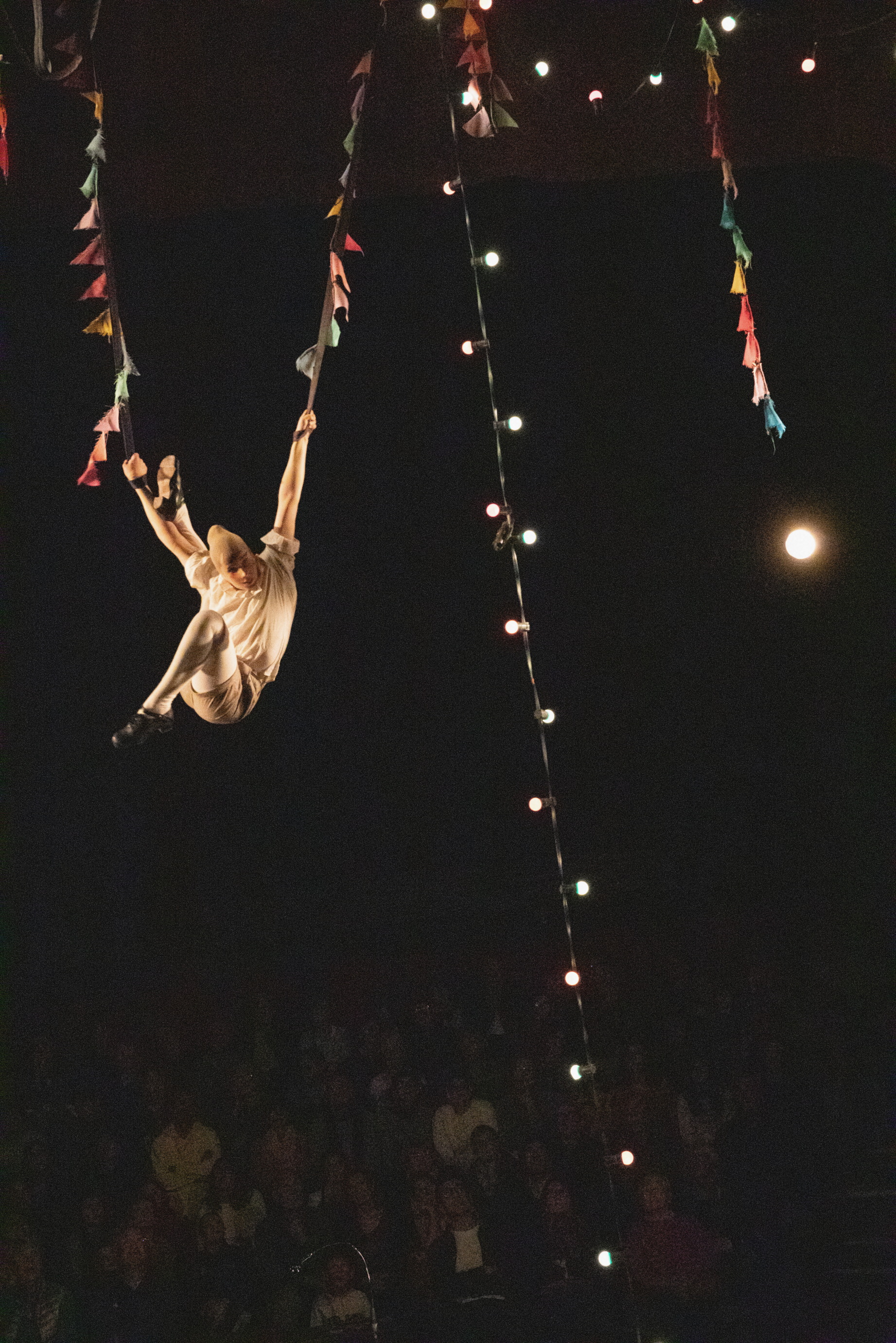 Clown hangt in de lucht in een circustent tussen vlaggetjes en lichtjes