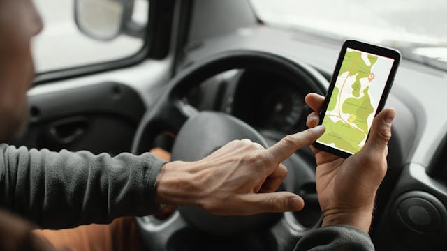 Man aan het stuur met smartphone