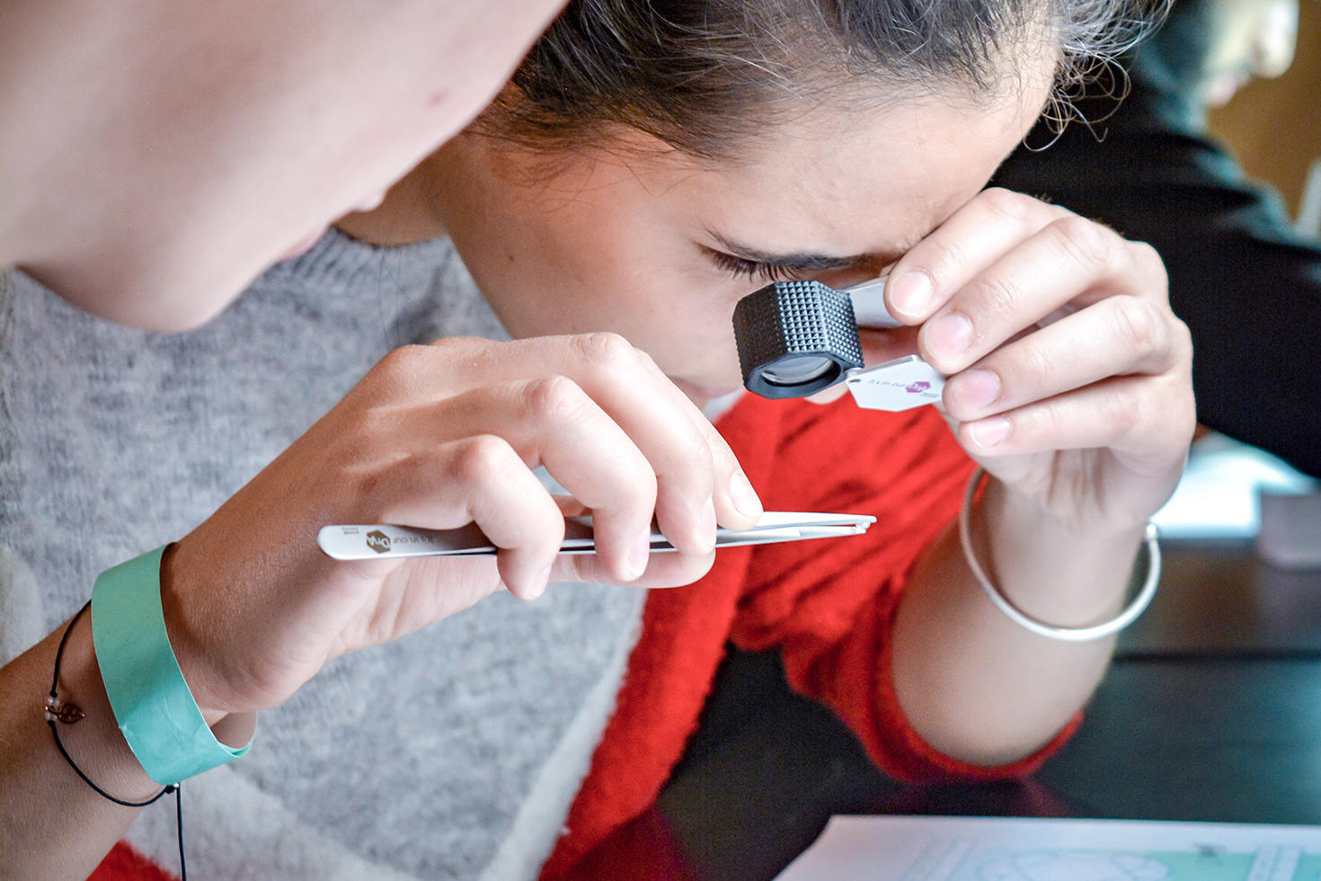 Meisje bestudeert diamant met loep en pincet