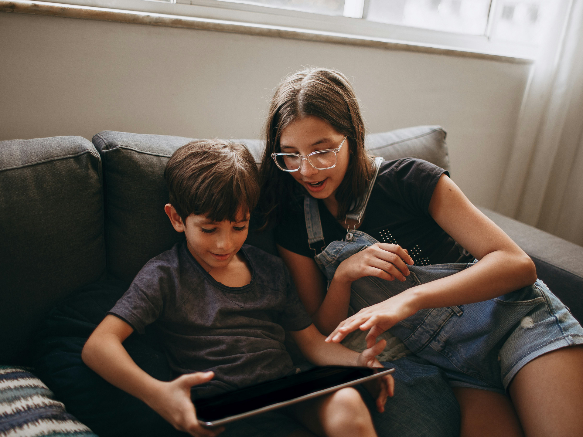 Jongen en meisje die in de zetel samen op de tablet werken
