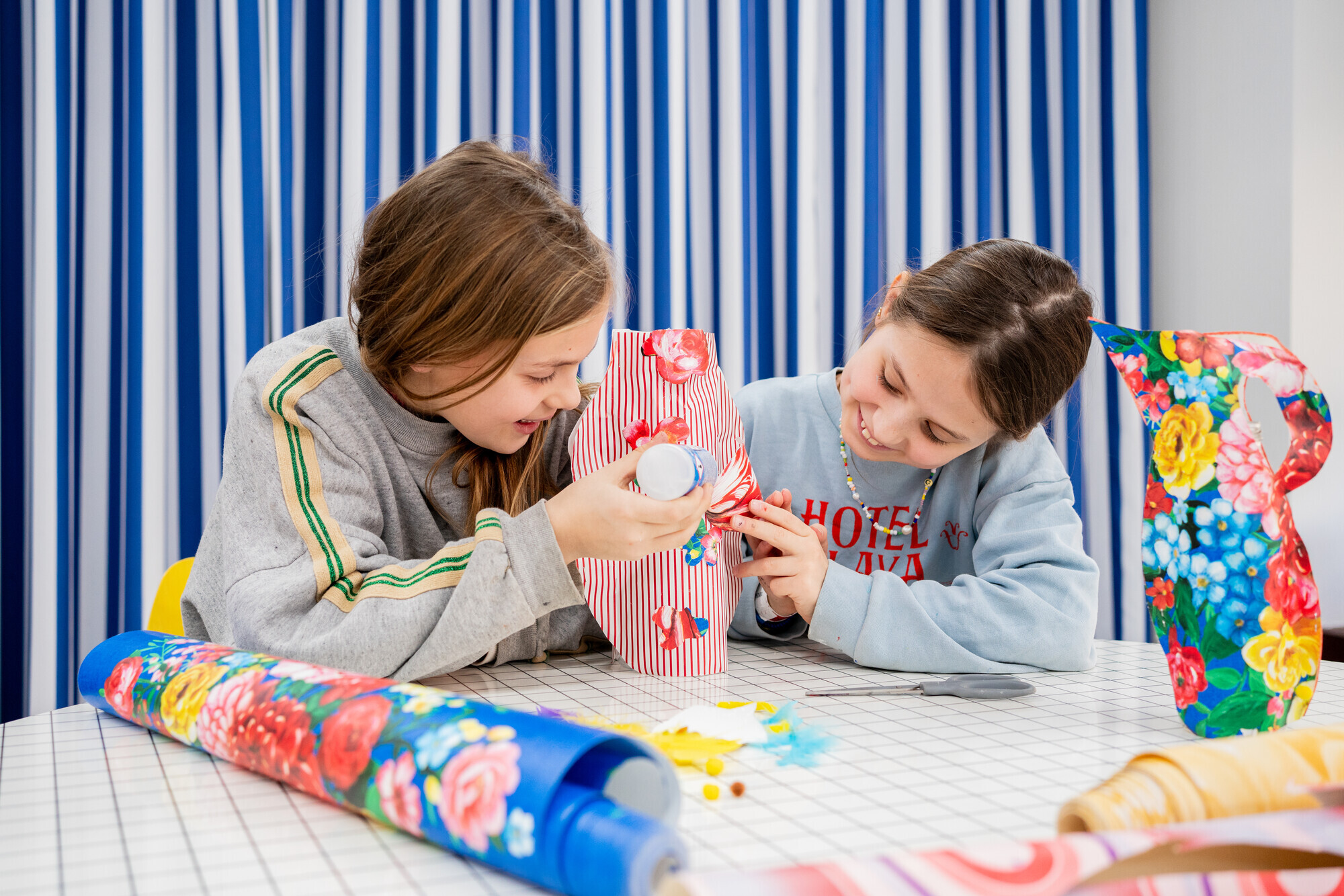 Twee kinderen lijmen aan een zelfgemaakte bloemenvaas