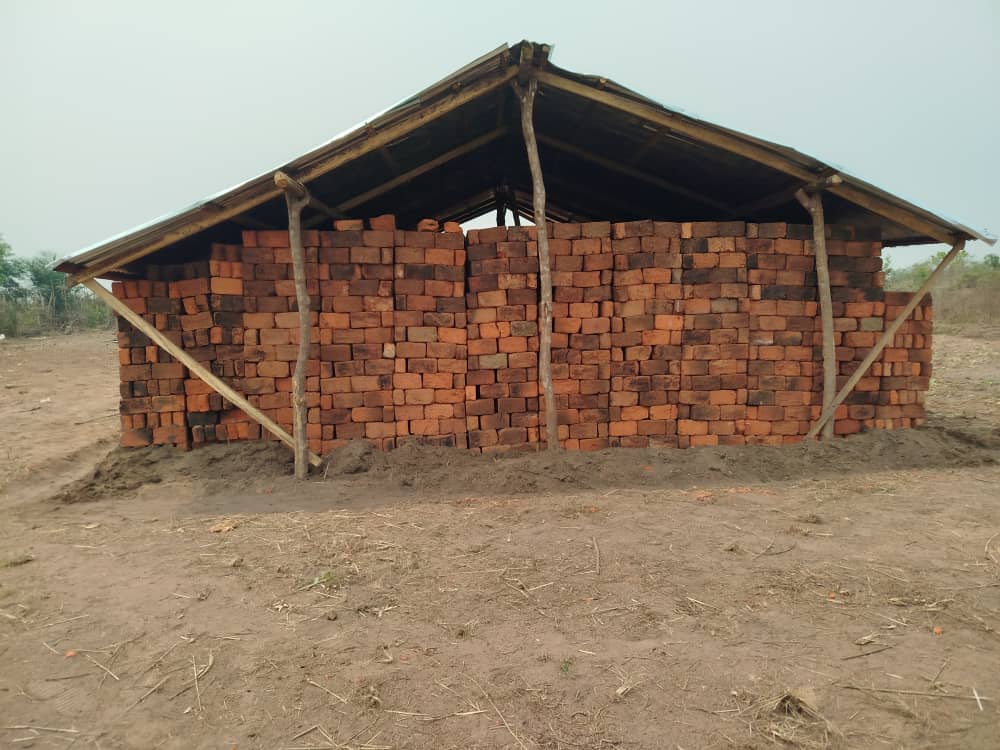 De artisanaal gebakken bakstenen worden bewaard onder deze hangar. Ze zijn voldoende om de eerste twee klassen te bouwen.