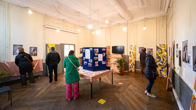 Een vijftal mensen bekijkt een tentoonstelling met foto's en tekstpanelen aan de muren