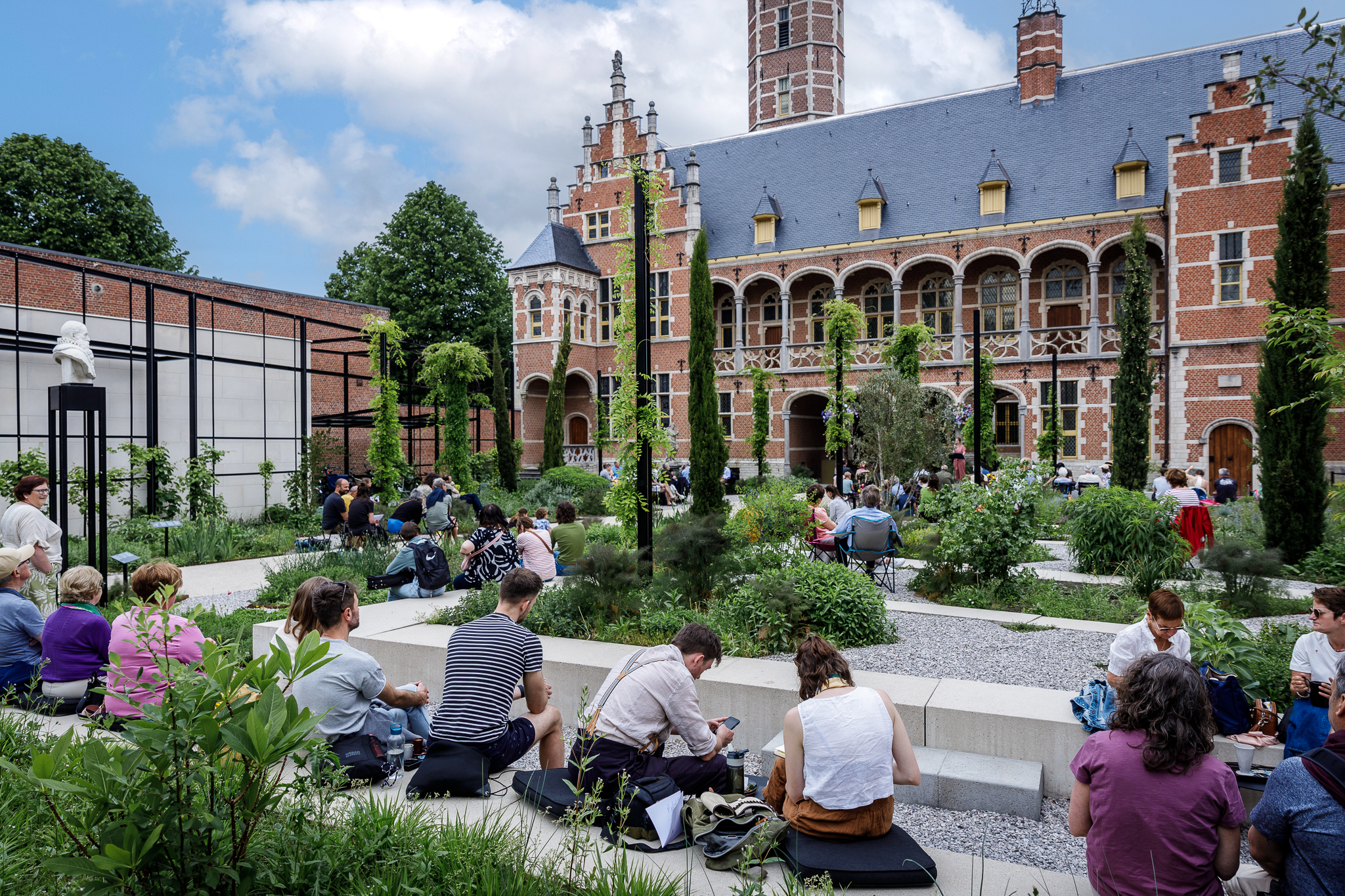 De museumtuin is gevuld met publiek dat naar het concert luistert.