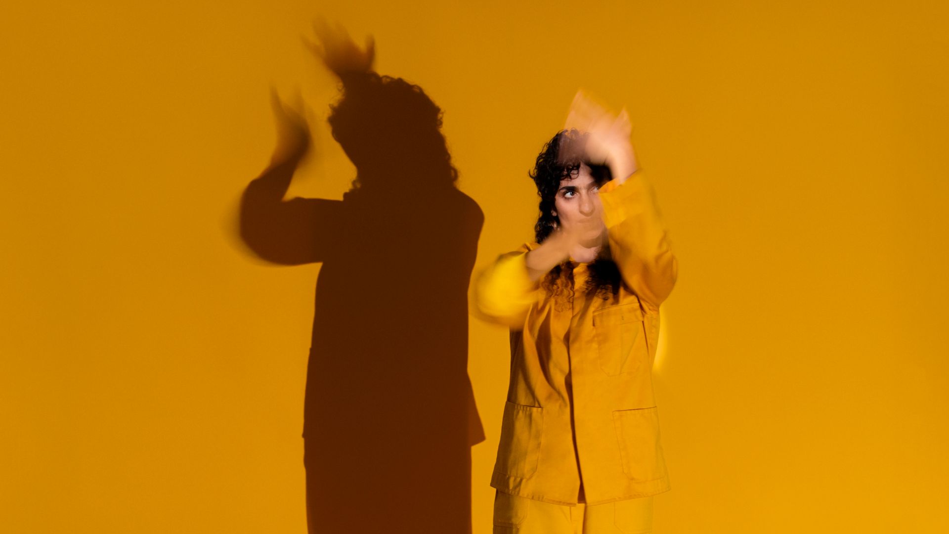 Danseres in geel pak voor gele achtergrond met schaduwbeeld
