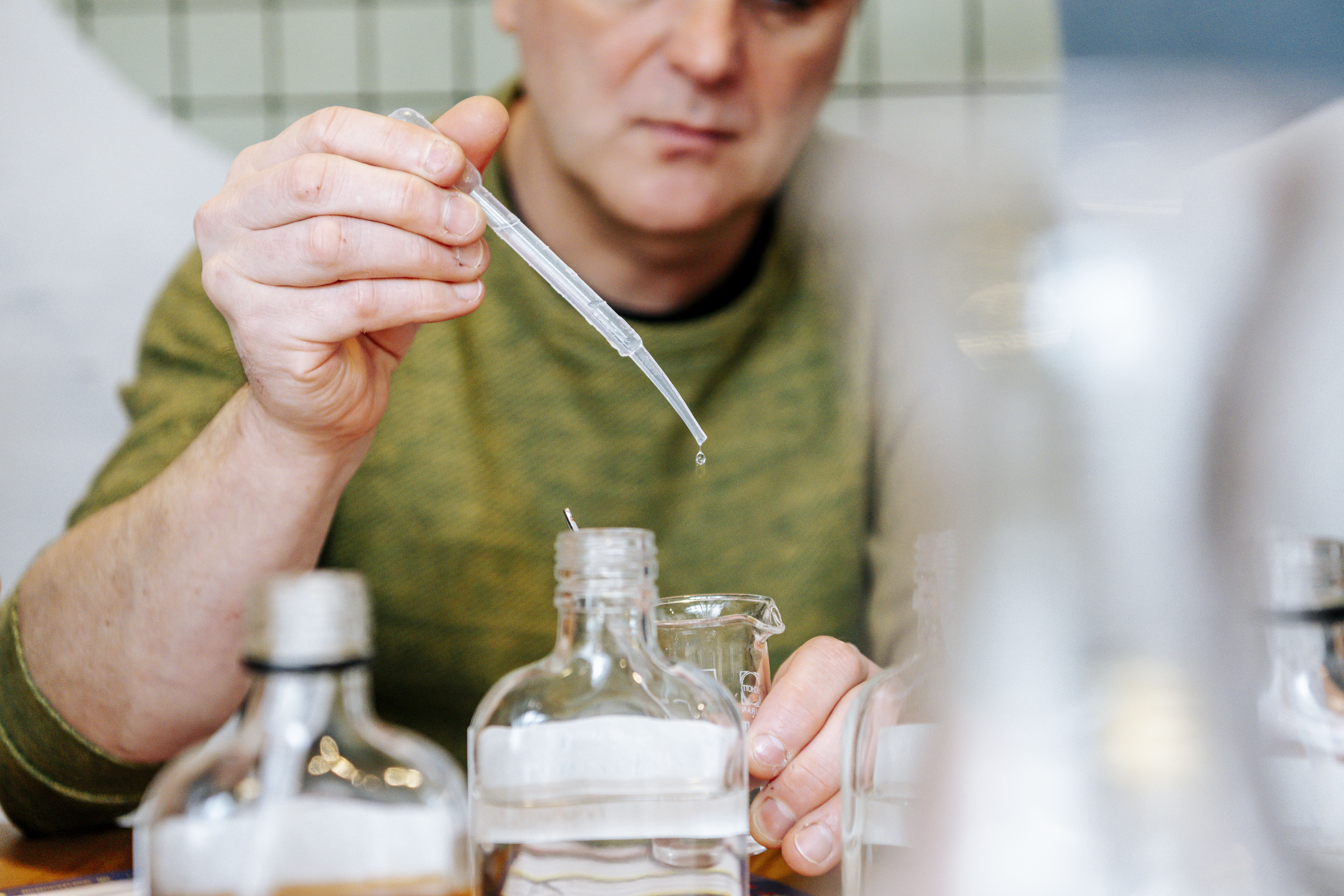 Workshop deelnemer experimenteert met druppels aroma bij het samenstellen van een eigen jenever