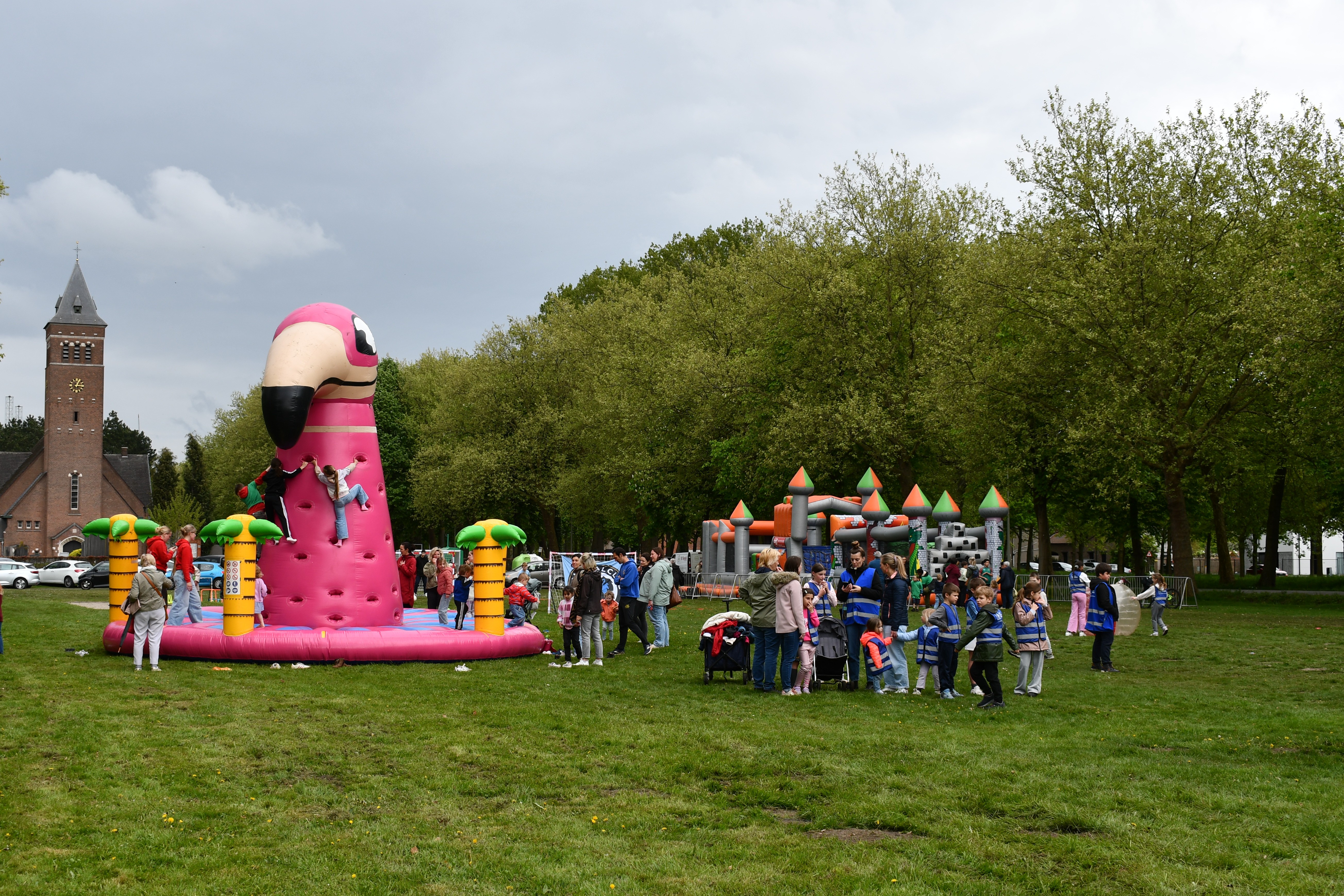 Kinderen die spelen op een grasplein naast een klimbaar luchtkasteel