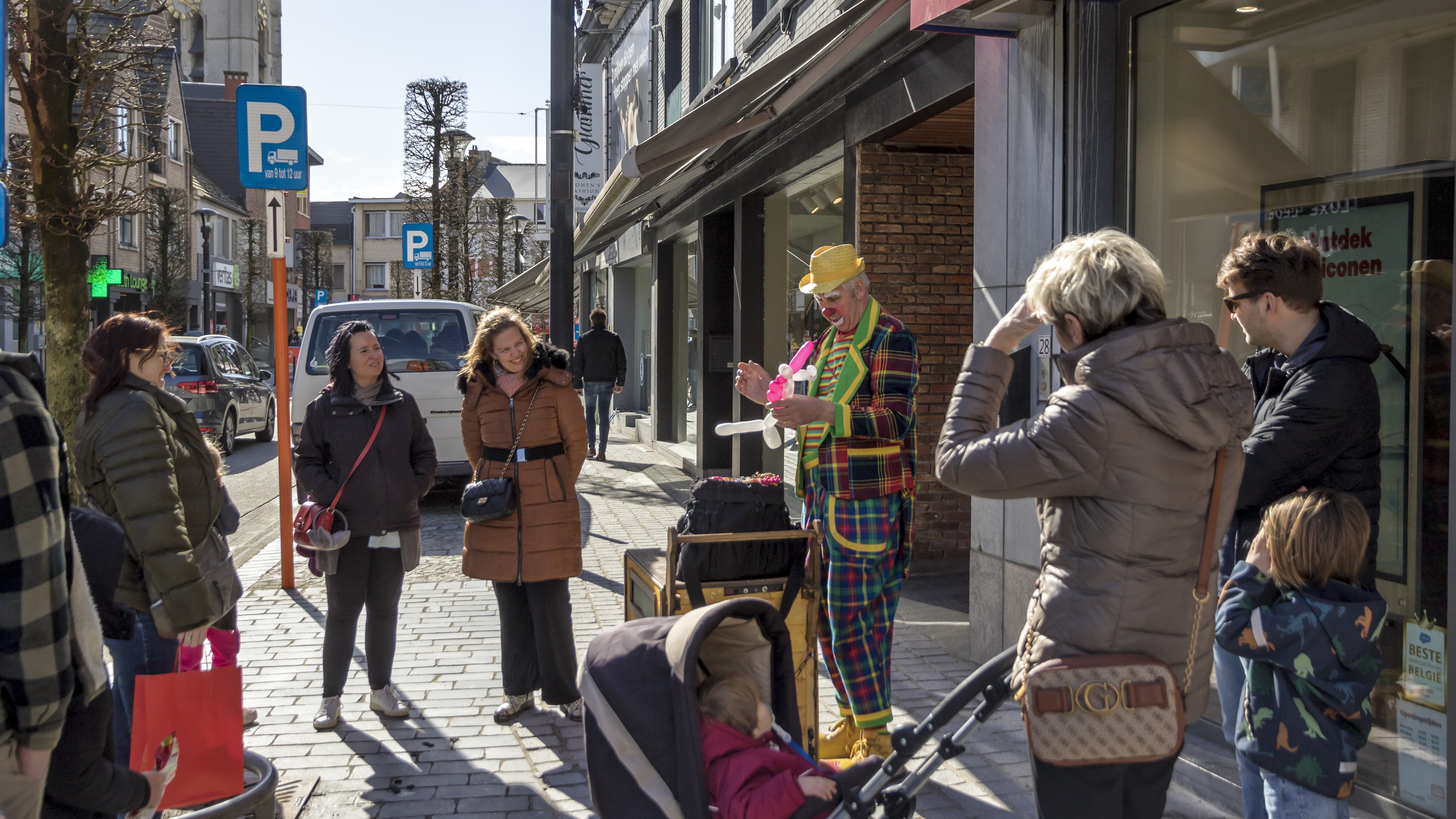 Shoppend gezin in winkelstraat met ballonplooiende clown