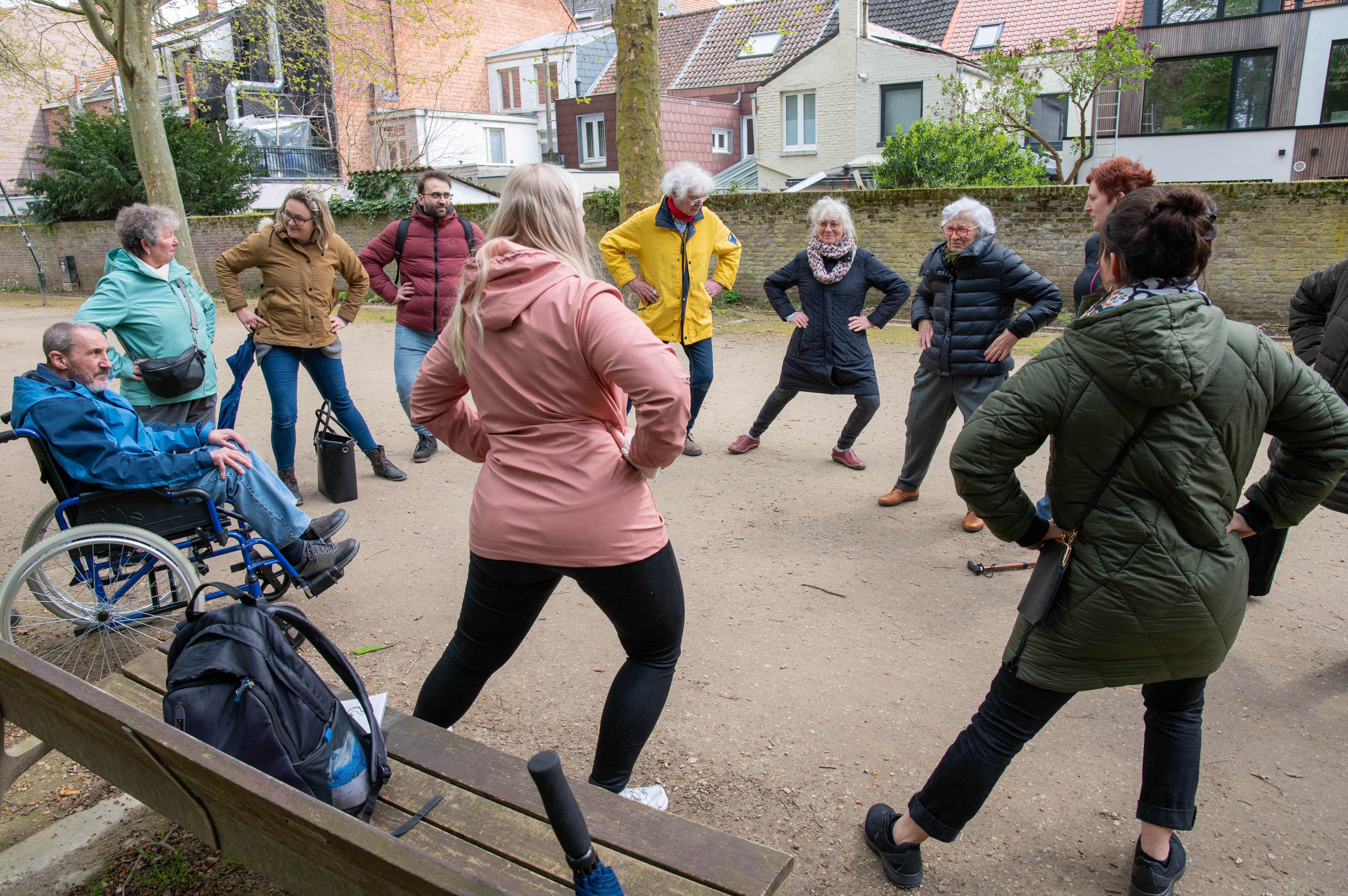 Wandelaars staan opgesteld in een cirkel terwijl ze onderweg een bewegingstussendoortje uitoefenen.