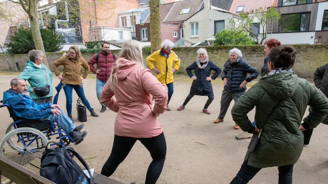 Wandelaars staan opgesteld in een cirkel terwijl ze onderweg een bewegingstussendoortje uitoefenen.