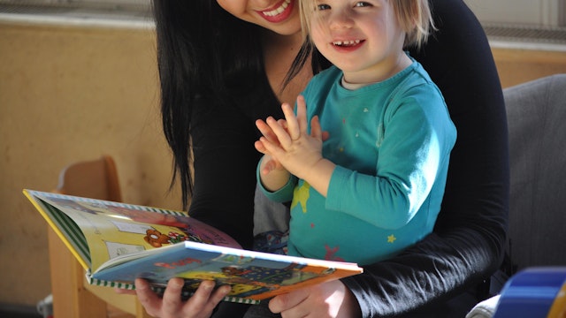 Vrouw leest samen met meisje een boekje van Pip en Posy.
