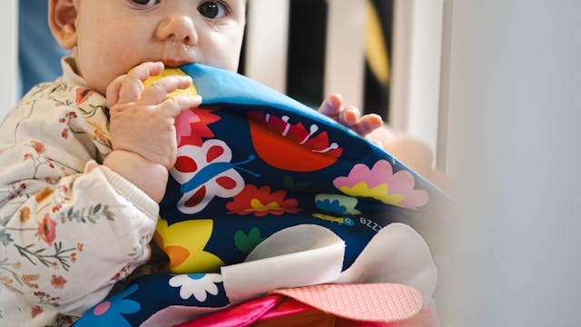 Een baby sabbelt op een voelboekje