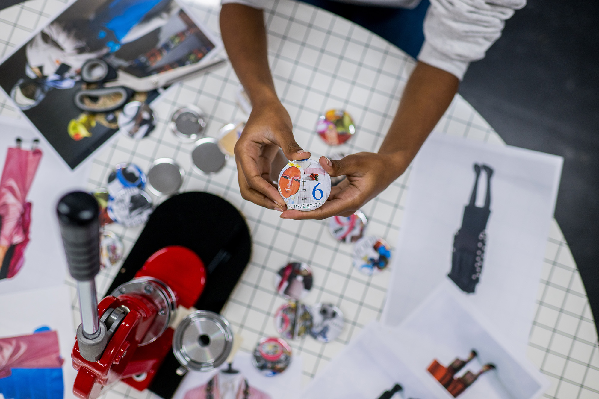 Buttons op een tafel met buttonmachine en kinderhanden