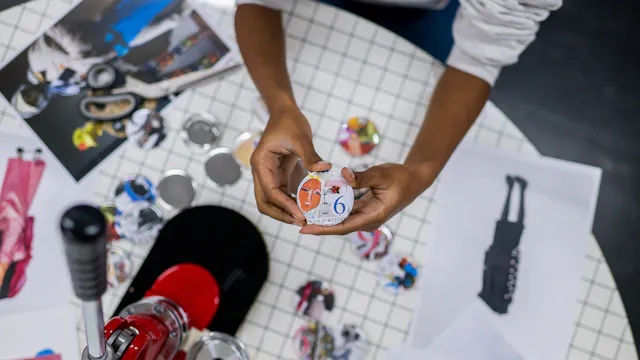 Buttons op een tafel met buttonmachine en kinderhanden