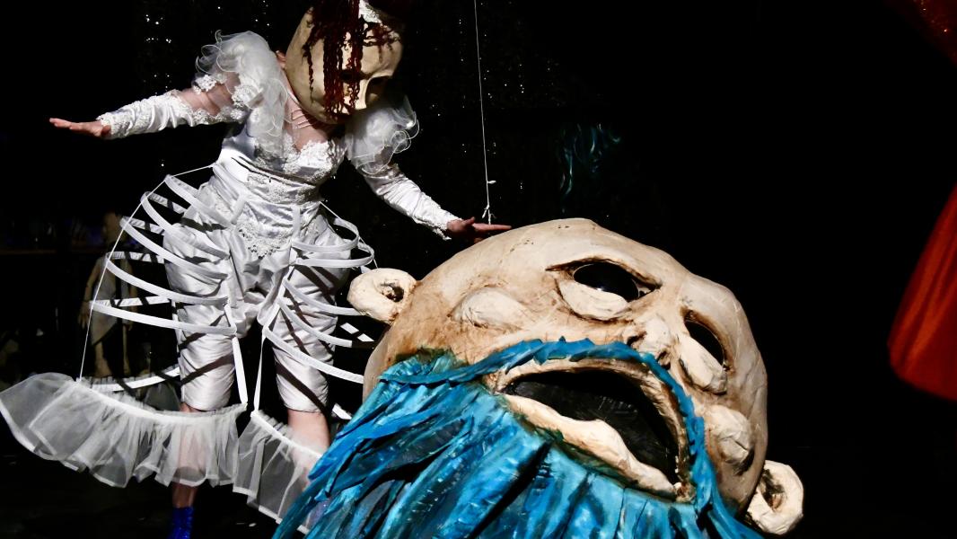 Iemand met een poppenhoofd op staat naast een gigantisch poppenhoofd.