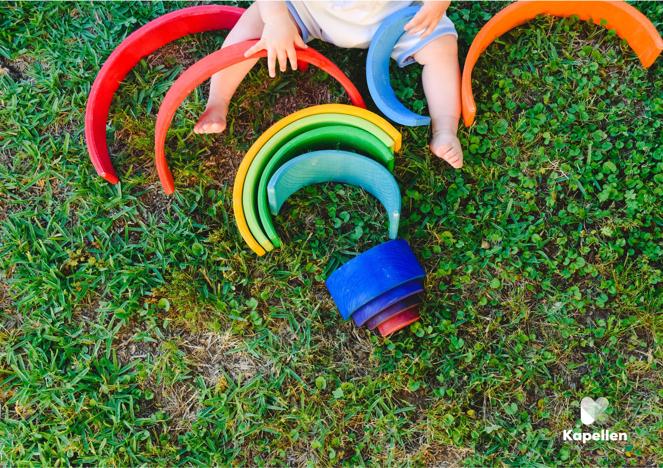 Kindje in het gras met speelbogen