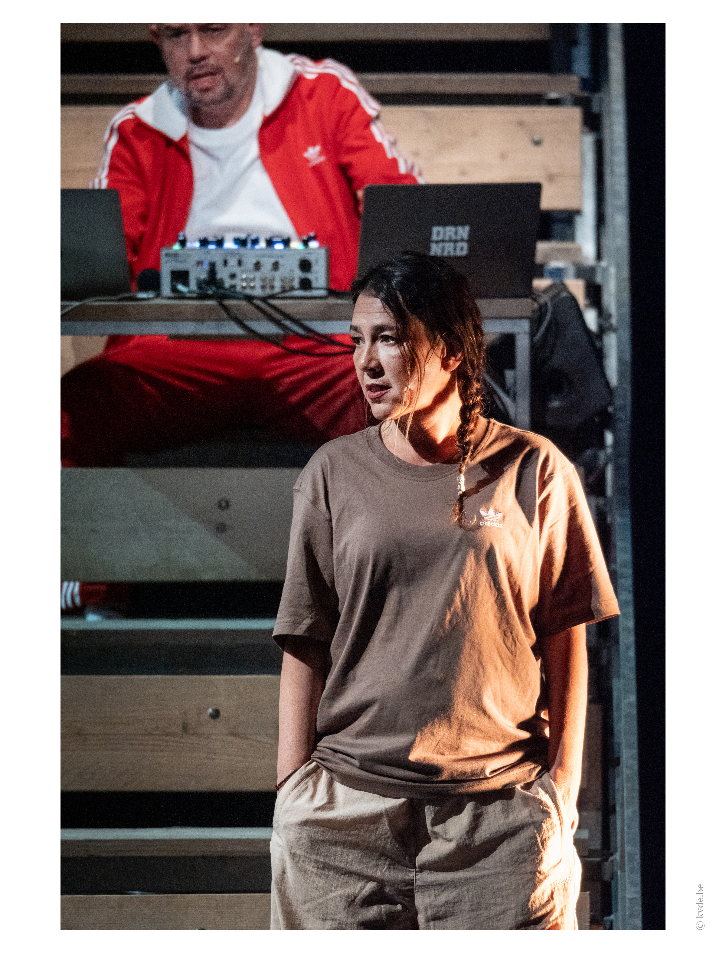 Een persoon die rechtstaat met de handen in de broekzakken. Iemand zit iets hoger achteraan.