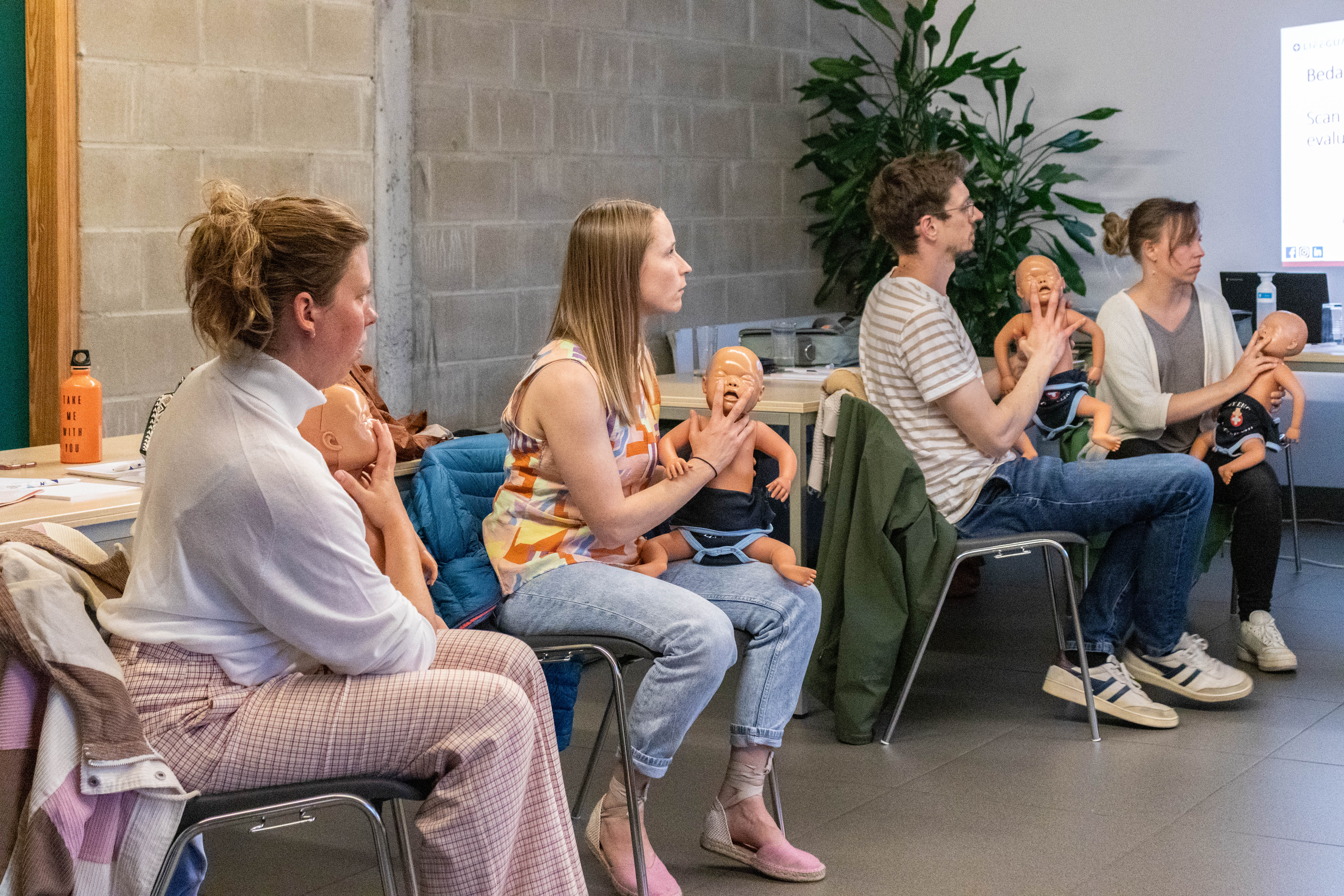 Cursus levensreddend handelen bij jonge kinderen, cursisten leren met een reanimatiepop van baby
