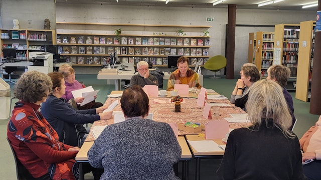 Mensen zitten rond een grote tafel in de leeszaal samen te lezen