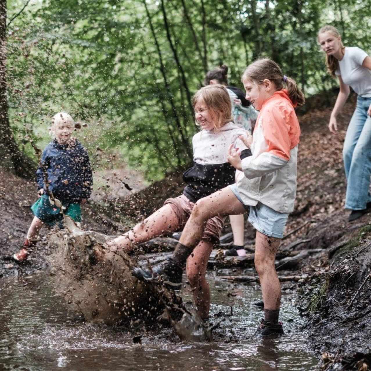 Kinderen spelen en ravotten in het bos tijdens het creatieve belevingskamp van CreatieKracht.