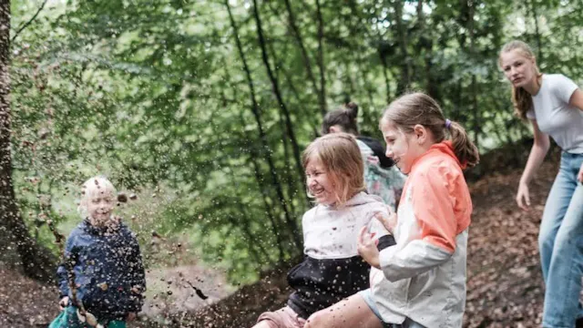 Kinderen spelen en ravotten in het bos tijdens het creatieve belevingskamp van CreatieKracht.