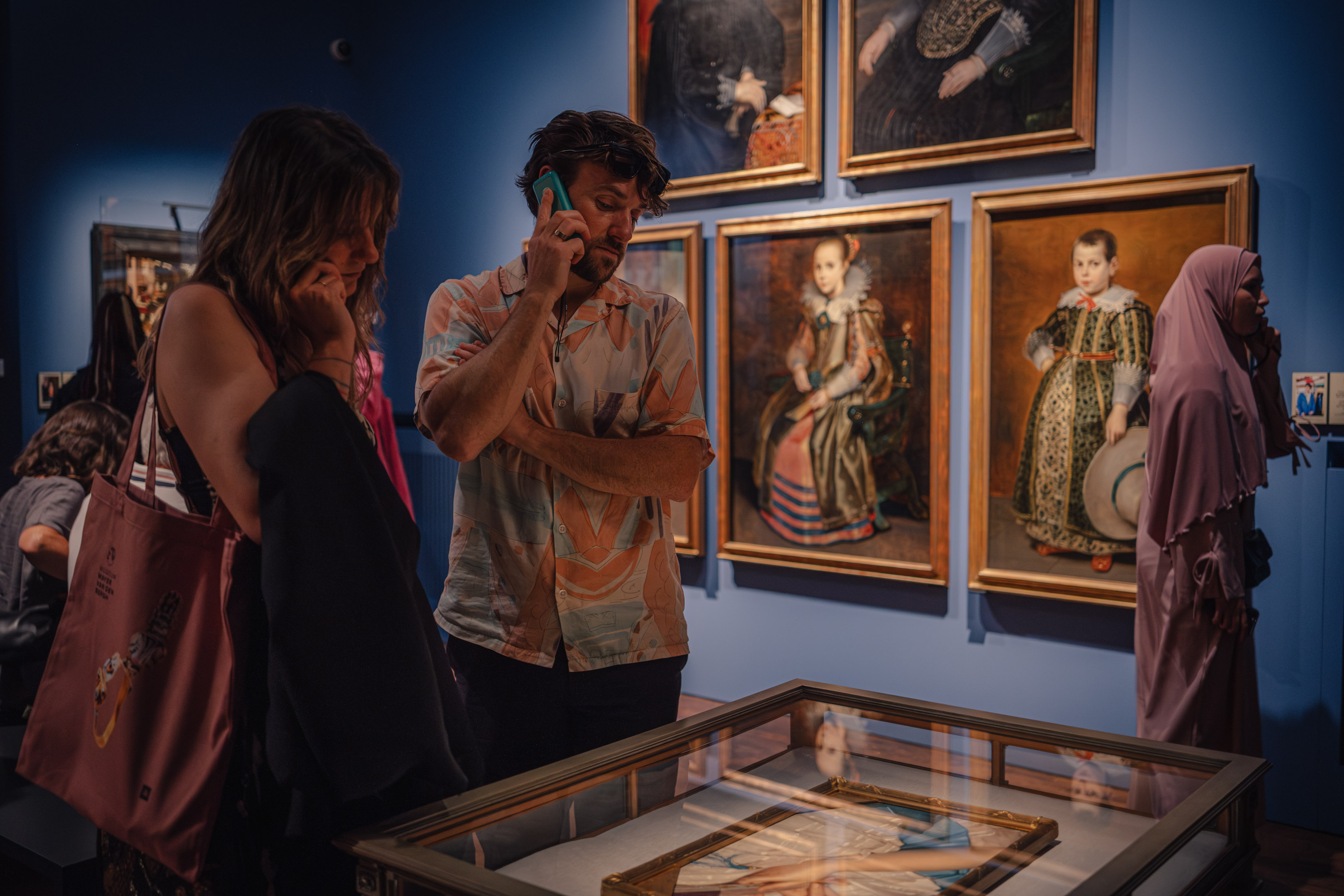 Een vrouw en een man kijken naar een schilderij en luisteren naar een audioguide.