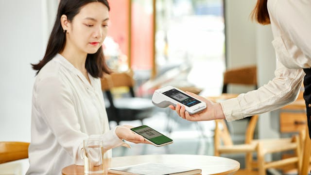 Dame die via de smartphone betaalt aan een mobiele betaalterminal