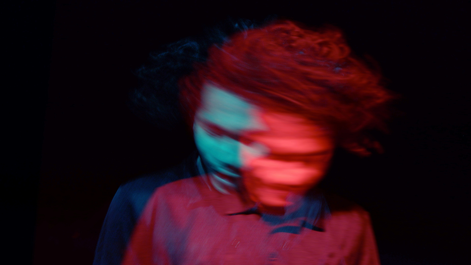 Bewogen van een man in rood en blauw licht op een zwarte achtergrond