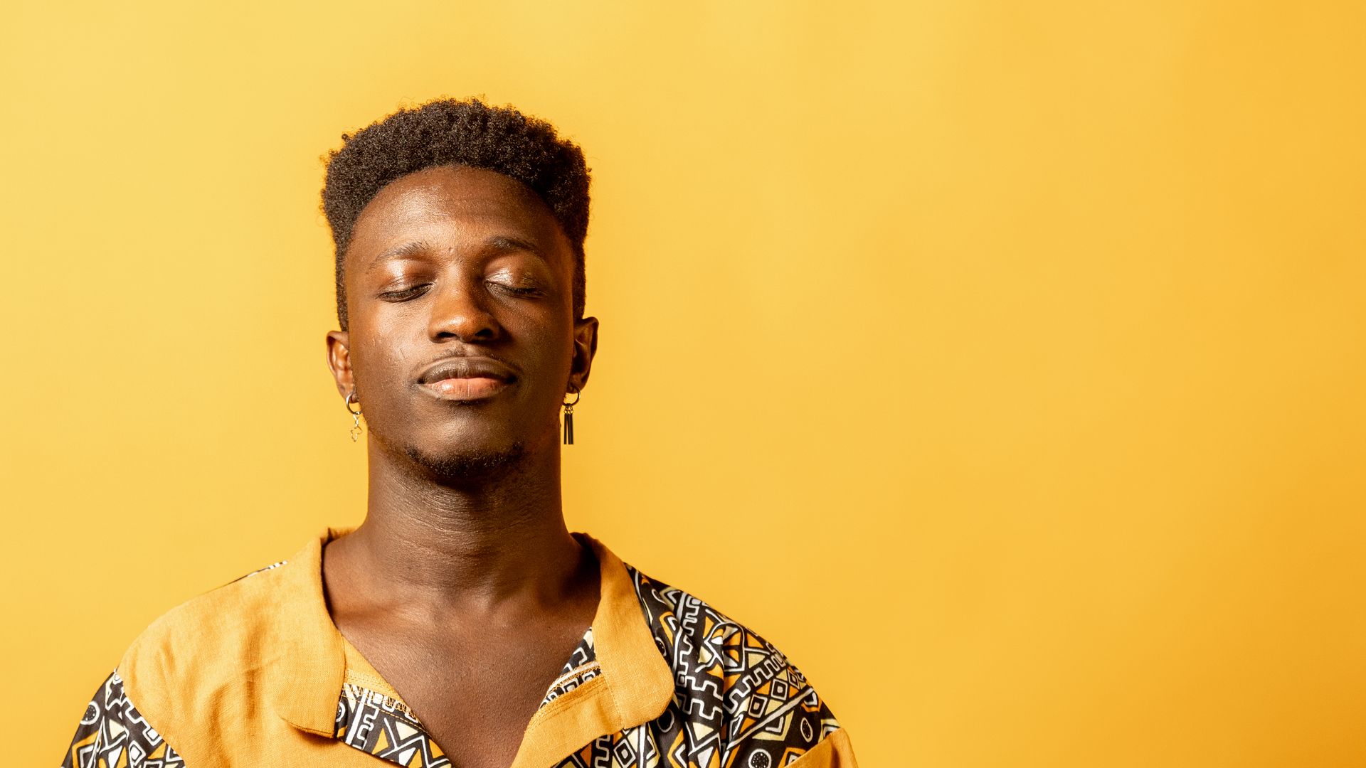 Momi Maiga in geel hemd voor gele achtergrond