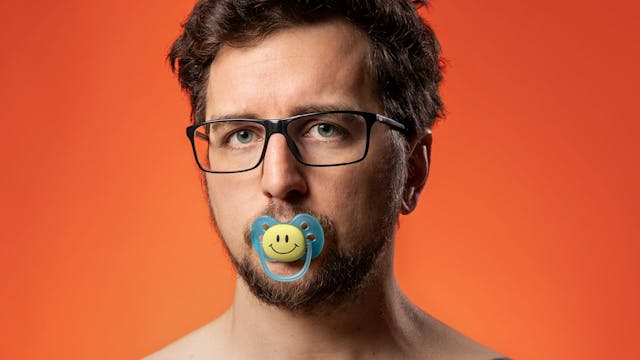 Jasper Posson met bloot bovenlijf en fopspeen met smiley in mond.