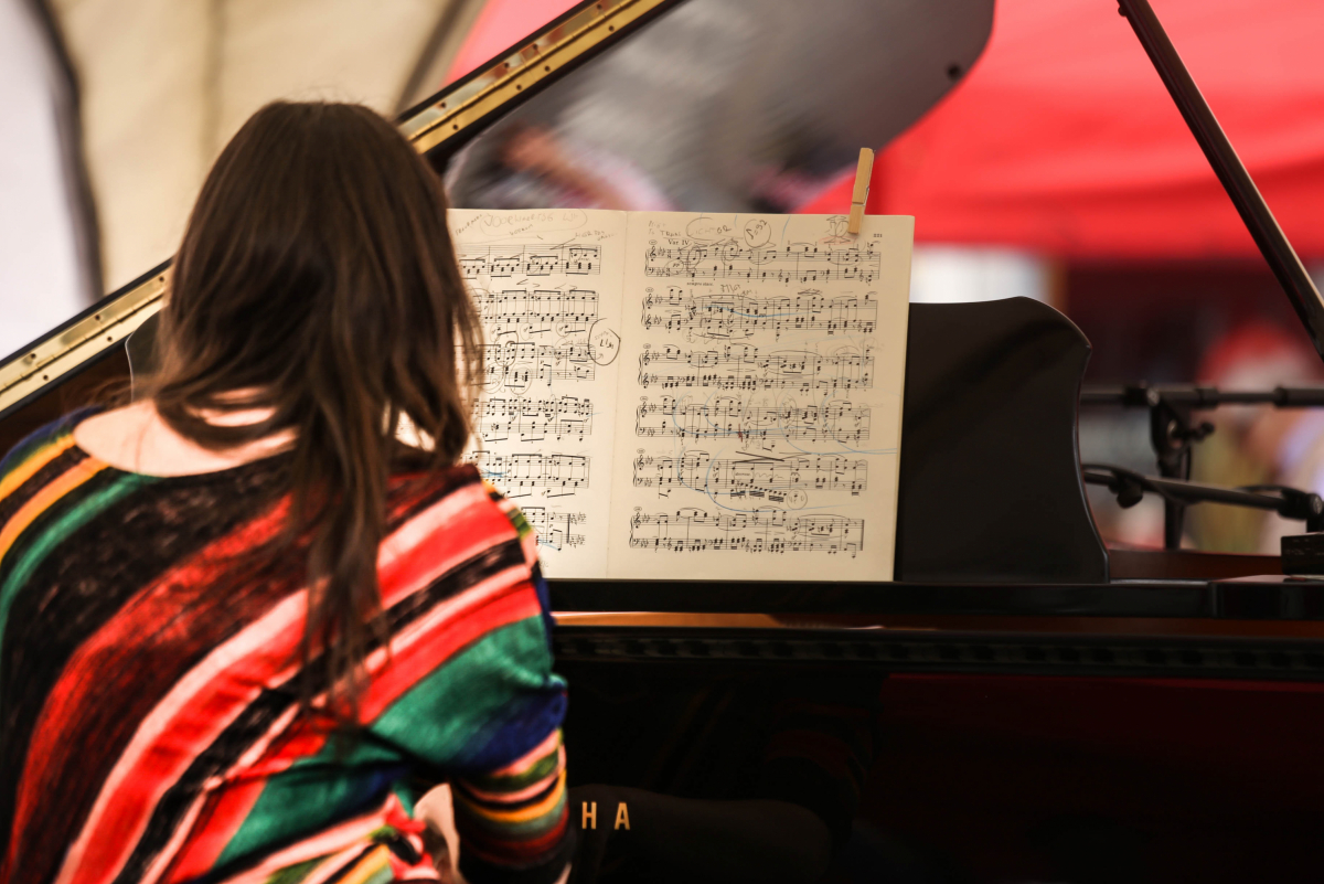 vrouw bespeelt een vleugelpiano en kijkt naar een partituur