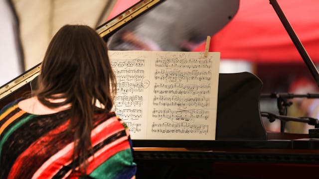 vrouw bespeelt een vleugelpiano en kijkt naar een partituur