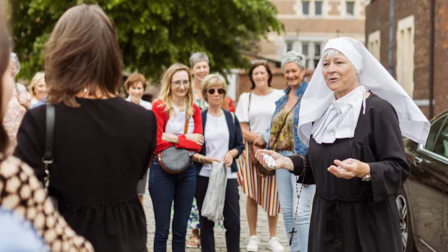 Gids verkleed als begijntje geeft uitleg