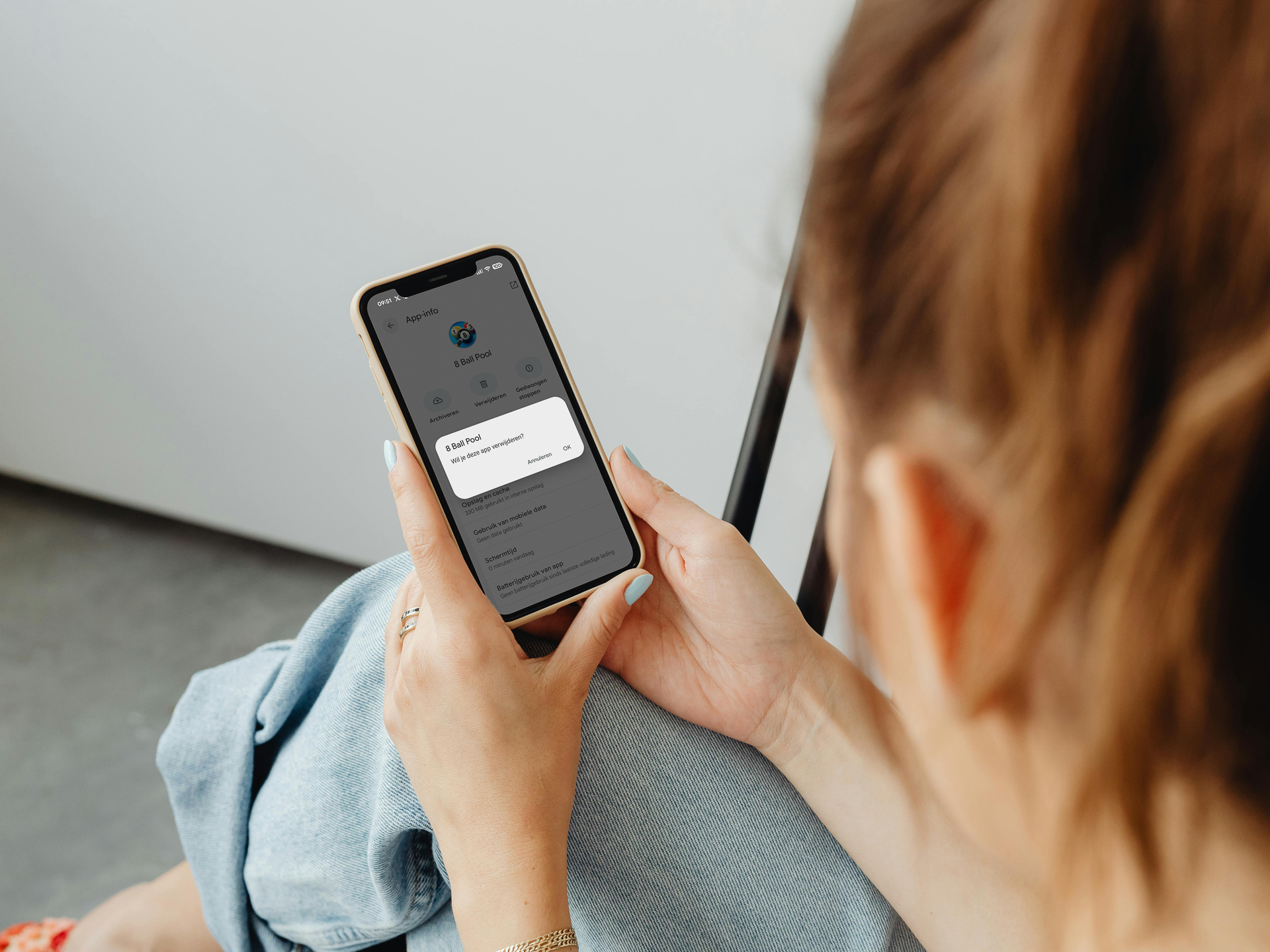 Dame die haar smartphone vasthoudt en via een pop-up op het punt staat een app te verwijderen
