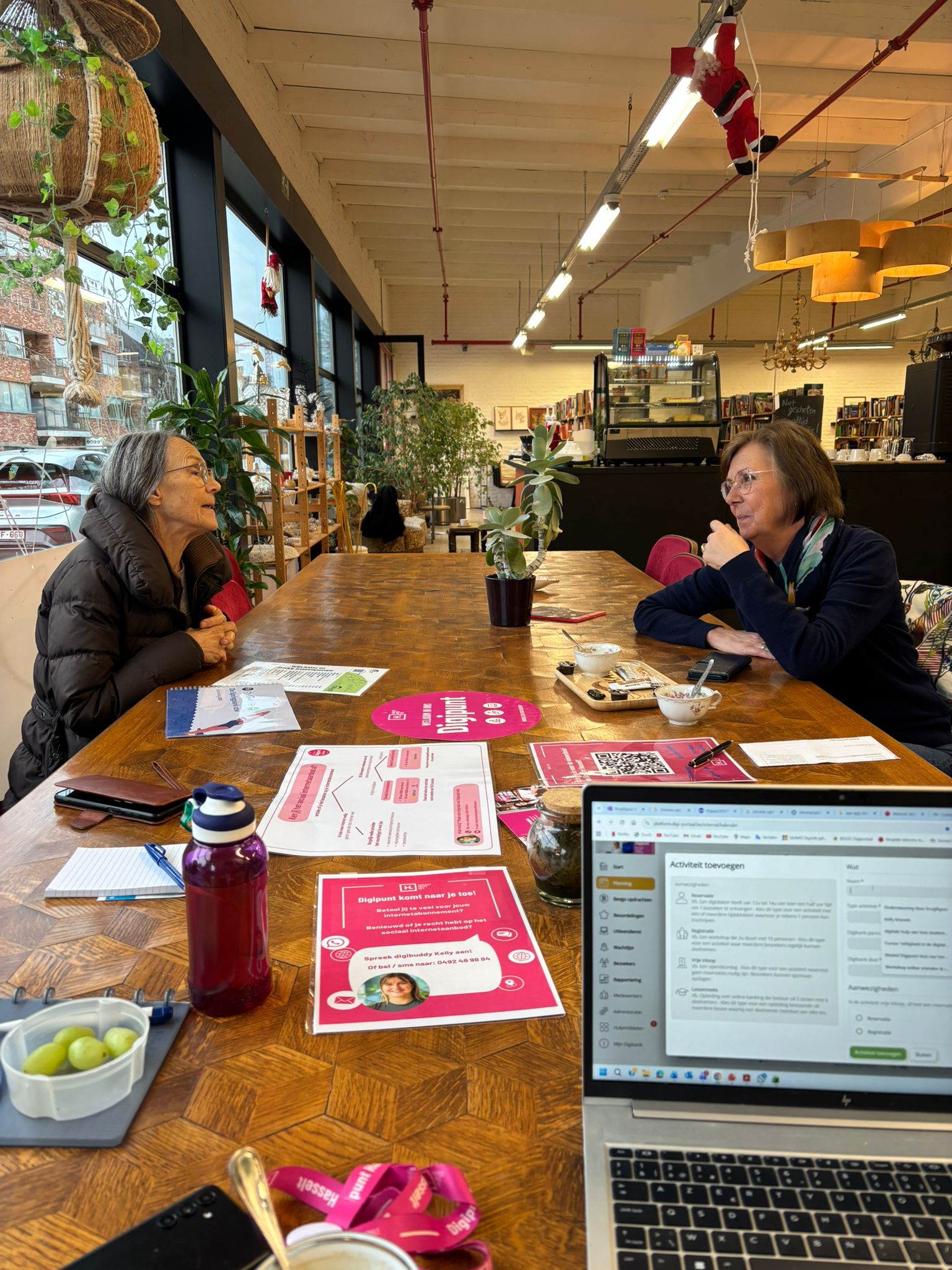 Twee dames die praten aan tafel en een laptop