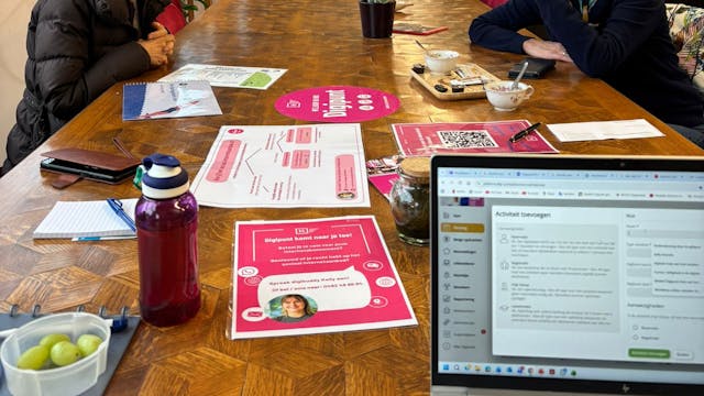 Twee dames die praten aan tafel en een laptop