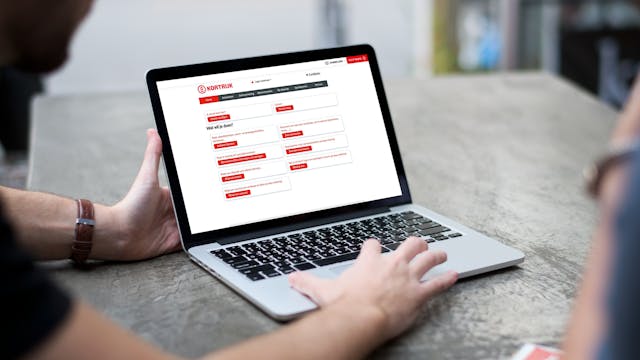 Persoon die iets toont op een laptop. Op de laptop is de homepagina van de webshop van Stad Kortrijk te zien