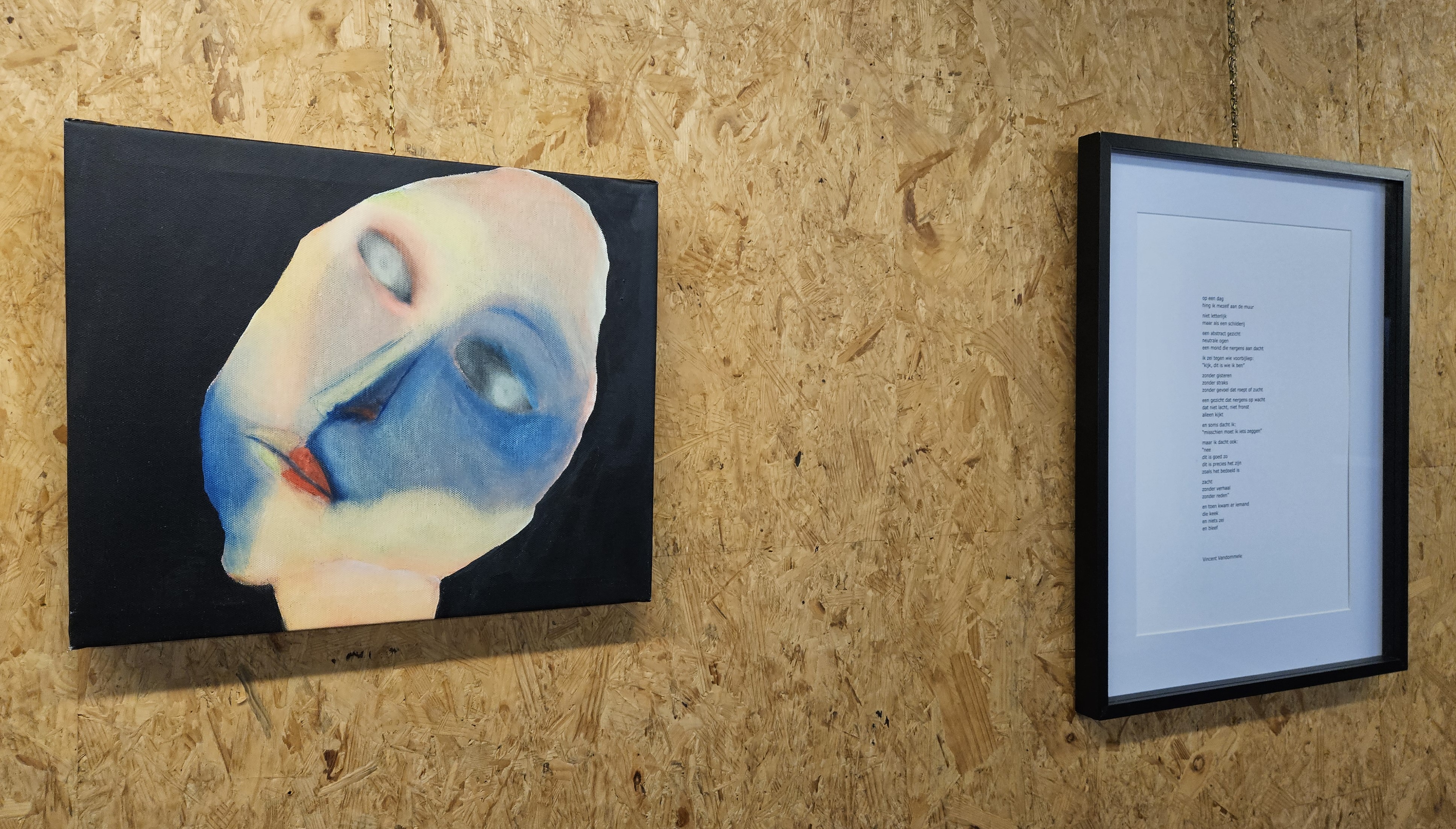 Een kunstwerk en een gedicht hangen naast elkaar aan een muur