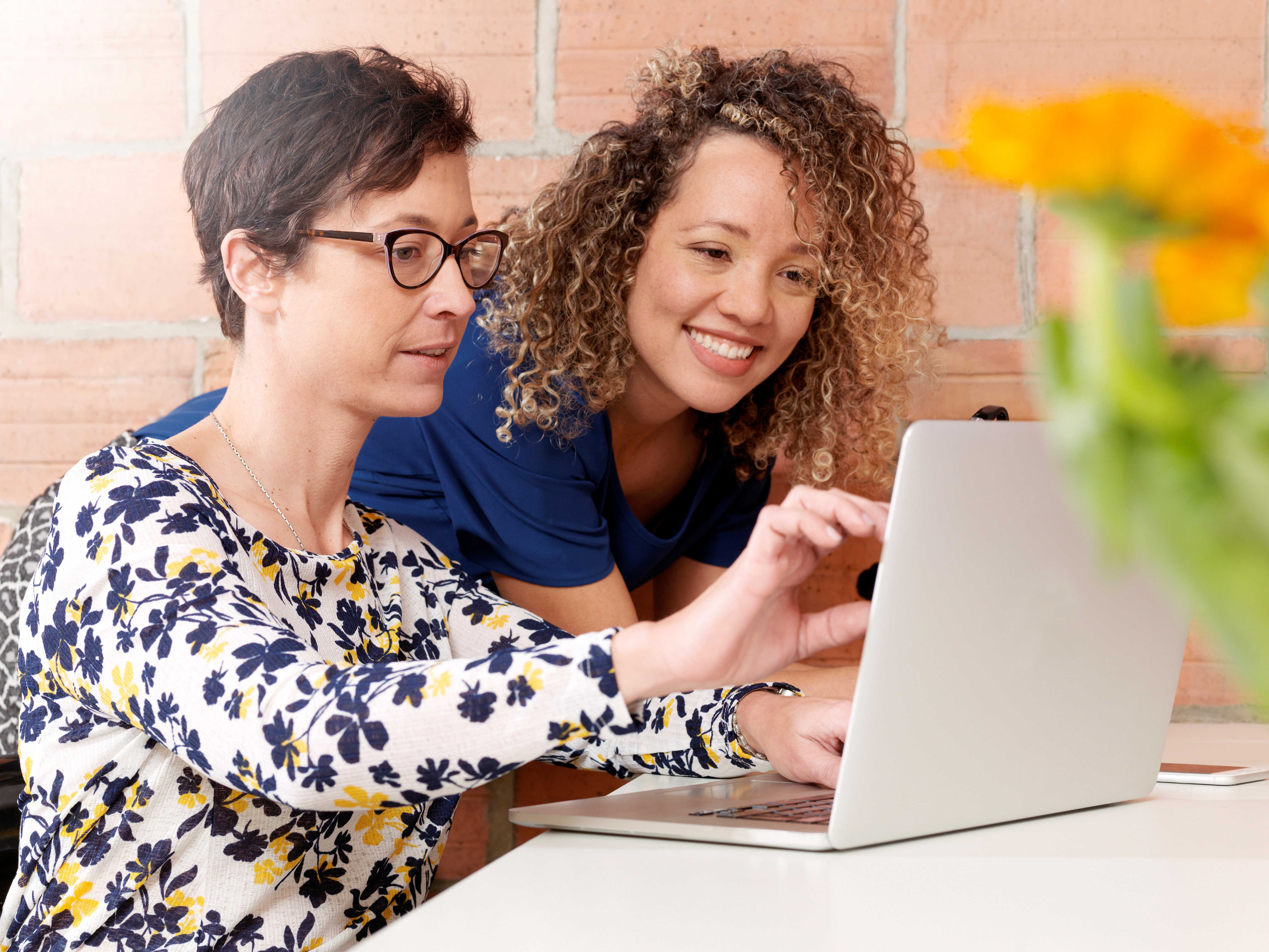 2 mensen zitten aan een laptop, de meest linkse raakt het scherm aan