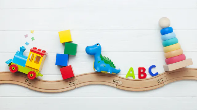 Speelgoed gestapeld naast elkaar op een houten speelgoedtreinspoortje