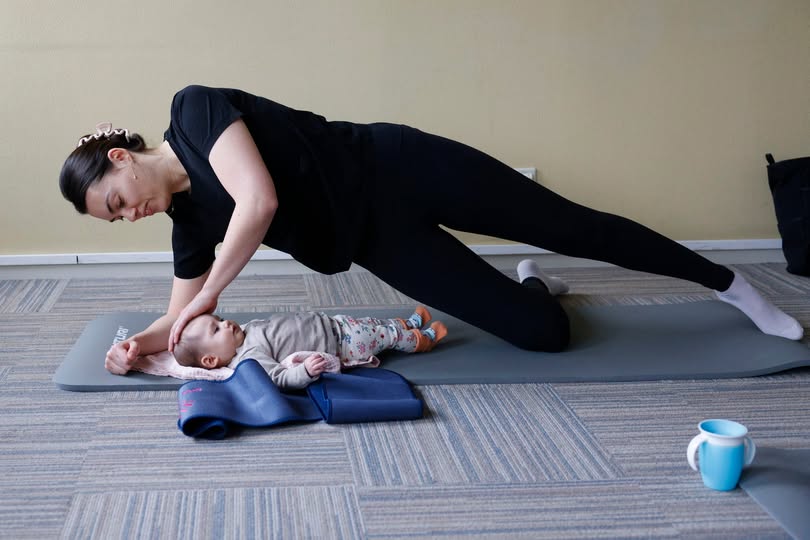 Een mama is samen met haar baby aan het sporten