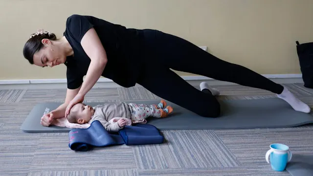 Een mama is samen met haar baby aan het sporten